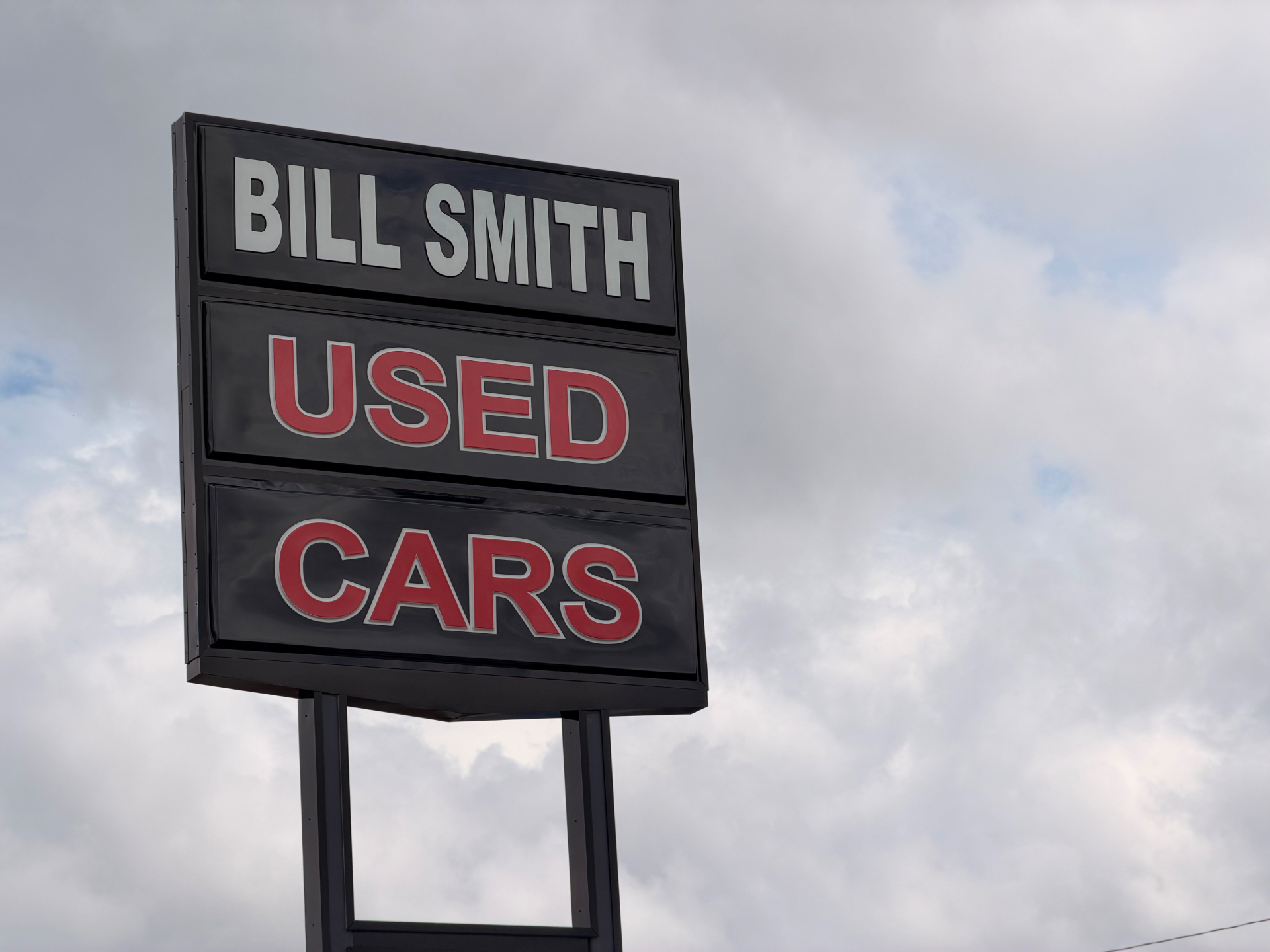 Bill Smith Used Cars sign against the sky
